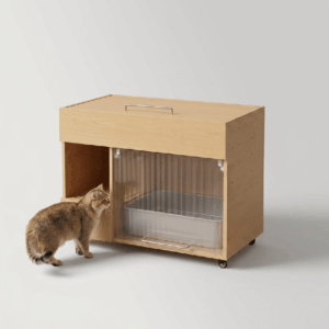 Hidden cat litter box furniture in pale natural oak wood with translucent ribbed sliding door, ventilation holes, and caster wheels, with a golden tabby cat standing nearby